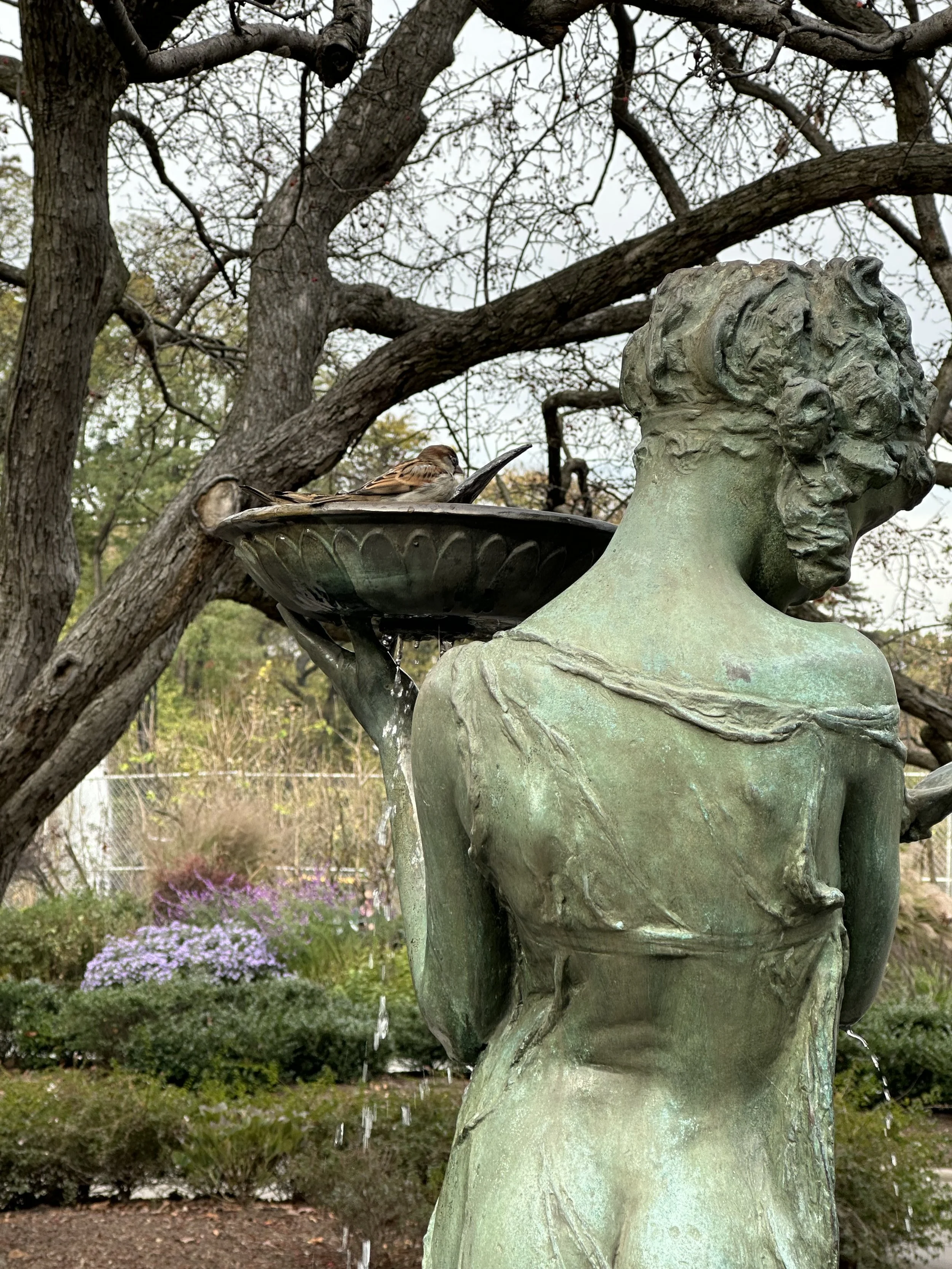 Girl with Birdbath: A quiet moment in the Conservatory Garden in NYC’s Central Park: she holds the birdbath gently, lost in the garden’s magic, as if inviting the world to pause and wonder.