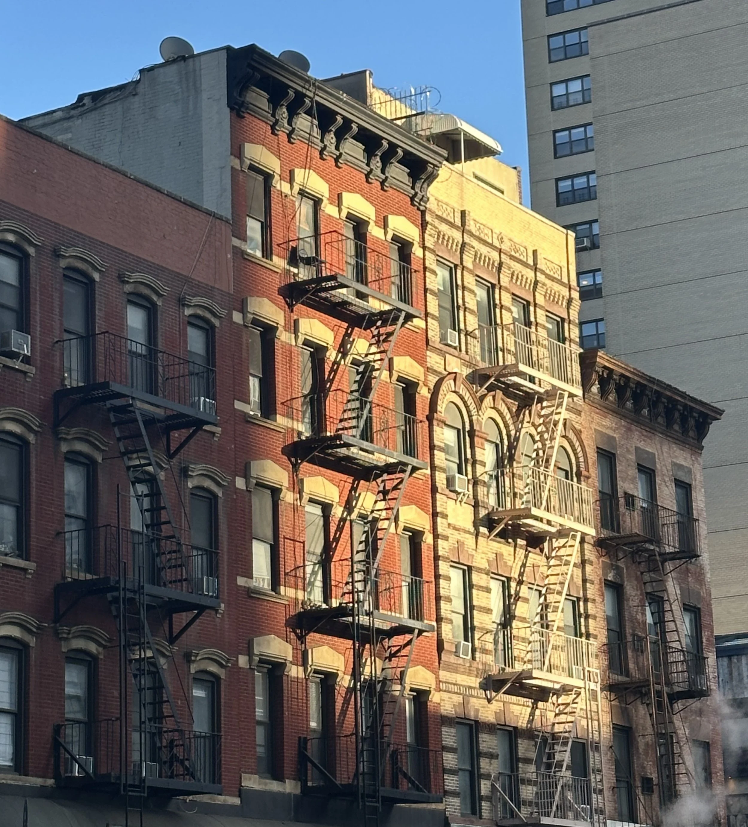 Classic NYC Buildings Kissed by the Sun: Sunlight warms these timeless tenements, turning everyday streets into a quiet, golden moment.