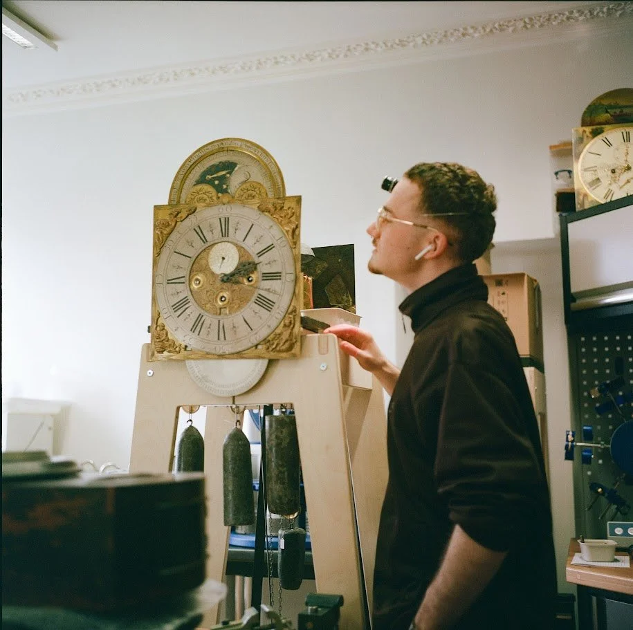 A horologist inspects his work on a longcase clock