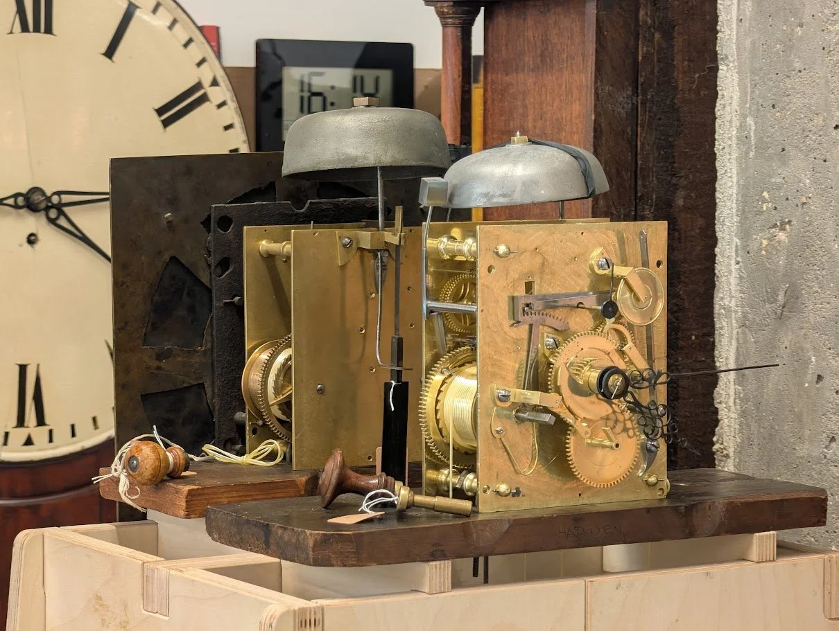 Two longcase clocks back to back on test. The one facing the viewer doesn't have its dial so all the mechanism is on show.