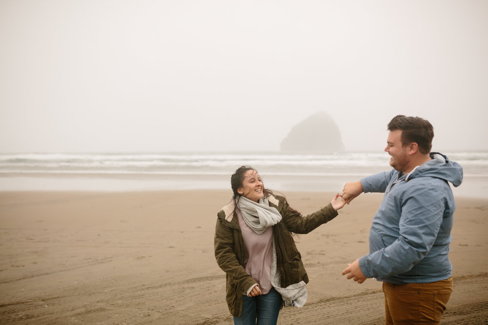 Happy young couple dancing on the beach in the wind and cold