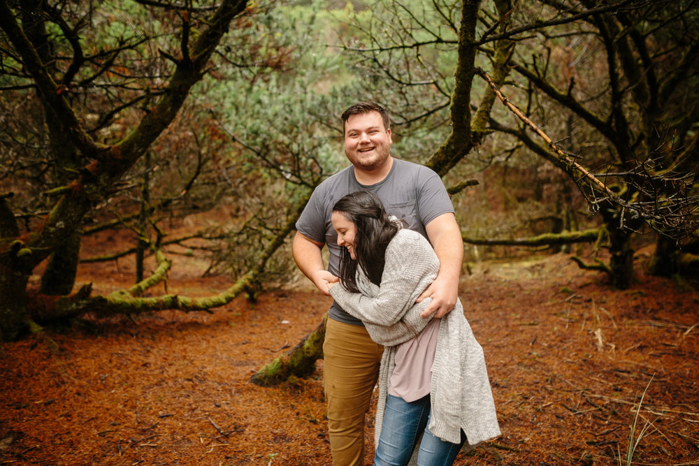 A happy young couple laughing and dancing amdist the trees near 