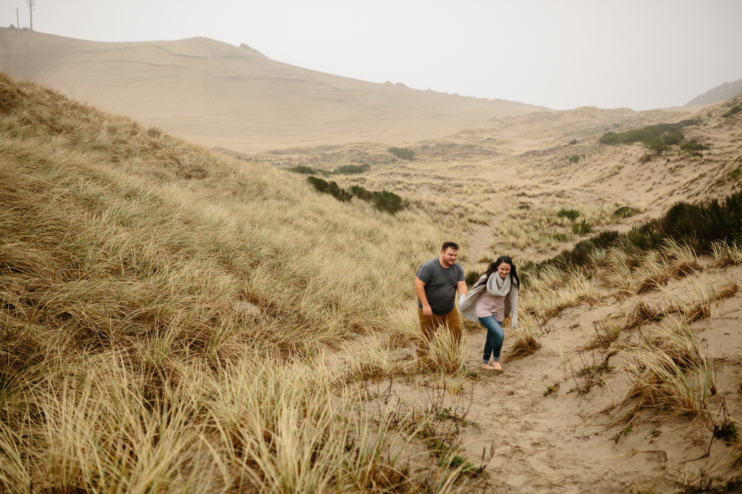 Portrait of a young couple walking through the sand and tall gra
