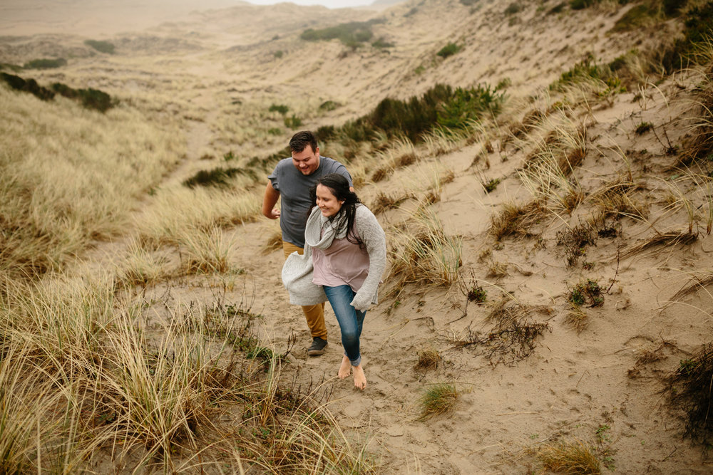 Portrait of a young couple walking through the sand and tall gra