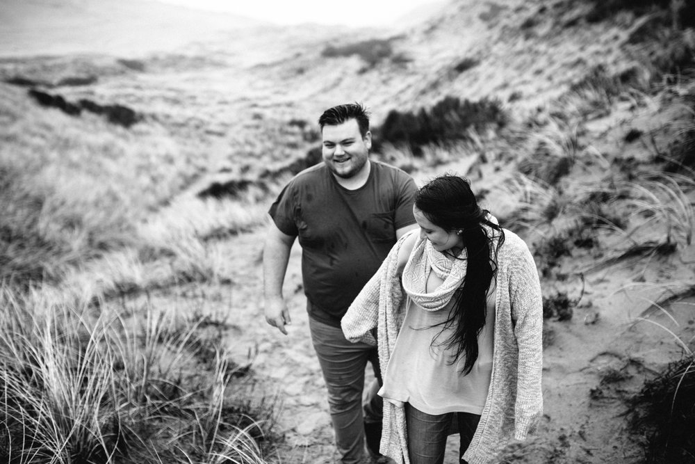 Portrait of a young couple walking through the sand and tall gra