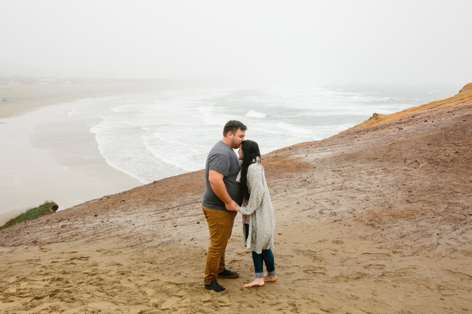A young couple embracing while standing on a large sand dune wit