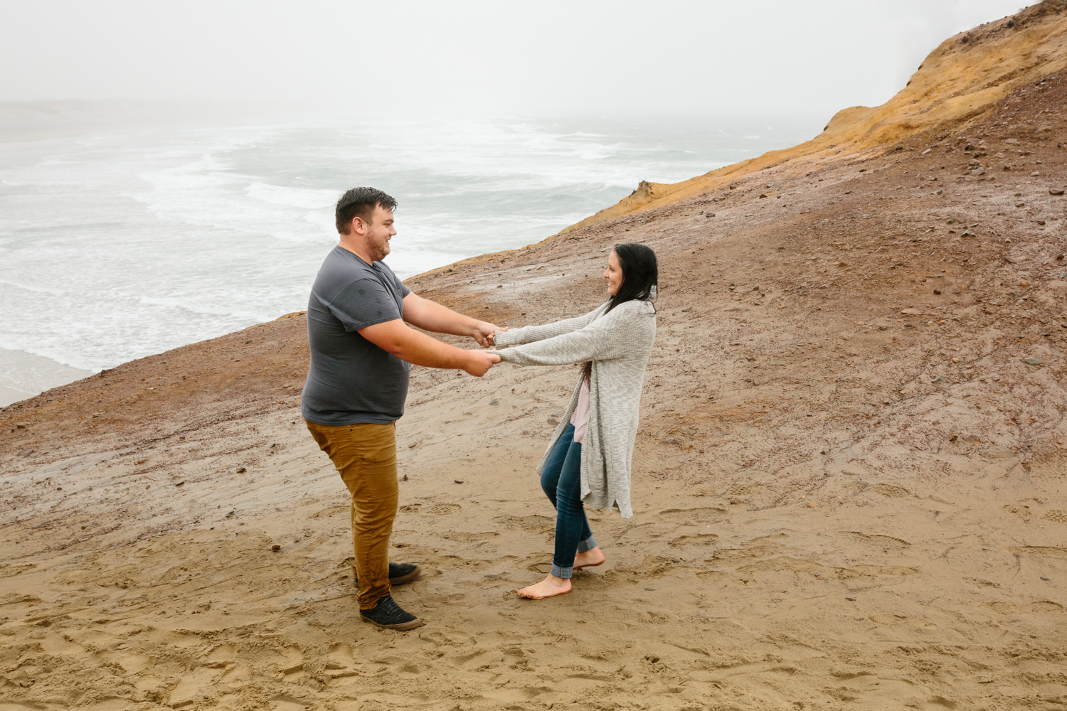 A young couple dancing while standing on a large sand dune with 
