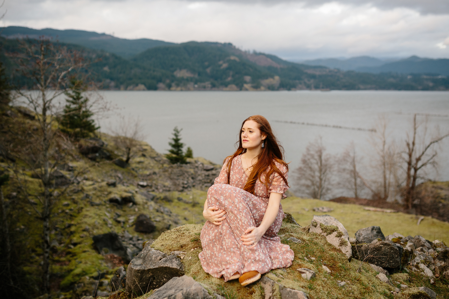 Portrait of a beautiful woman sitting on a moss covered boulder 