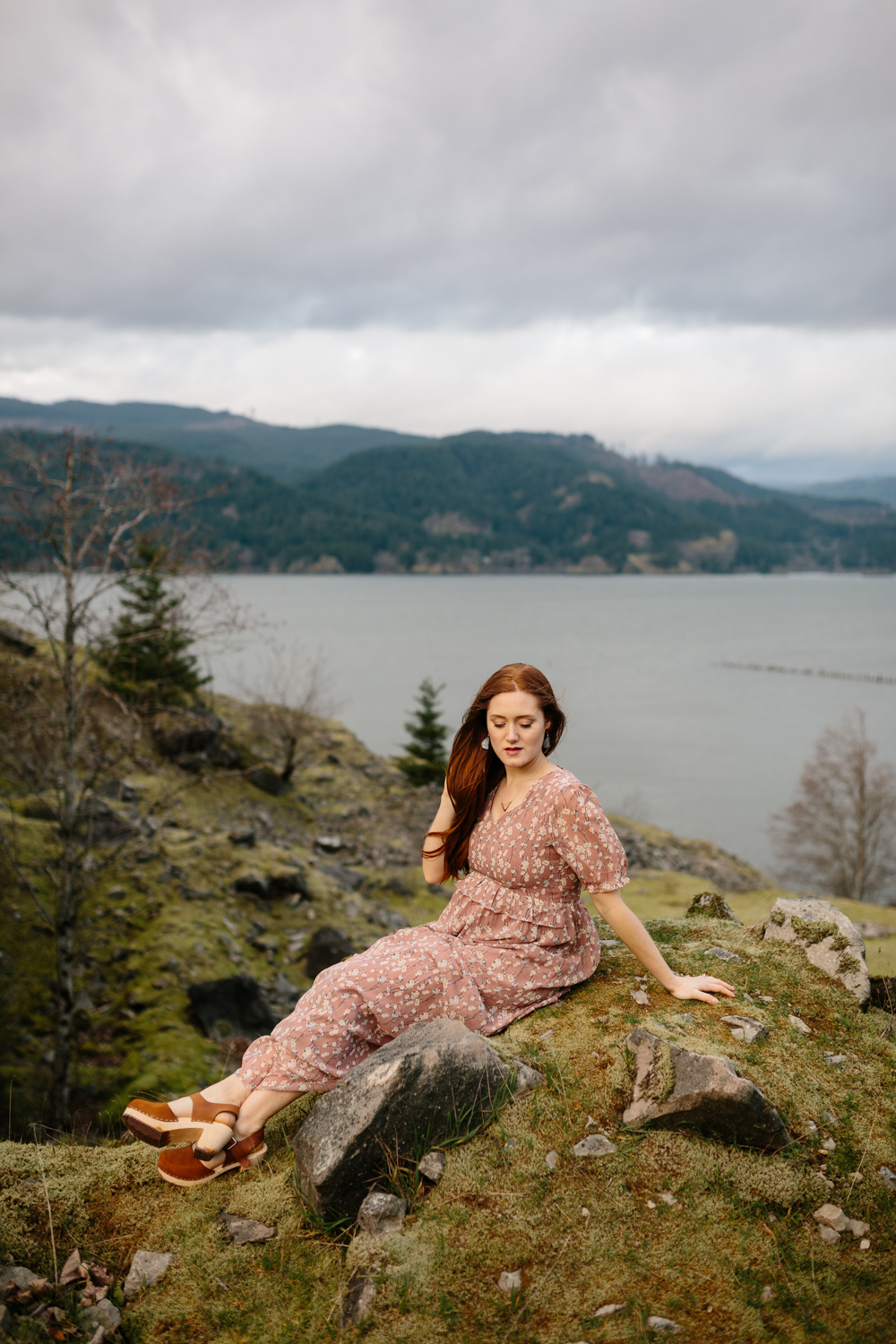 Portrait of a beautiful woman sitting on a moss covered boulder 