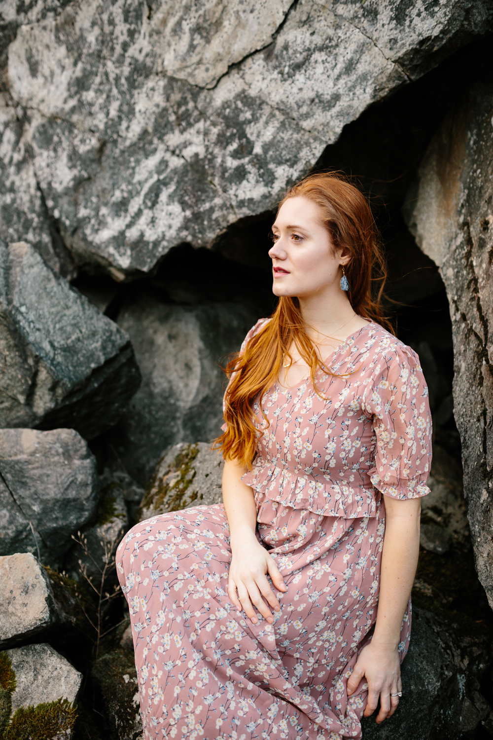 A Portrait of a Beautiful, Red-Haired Woman Sitting Amidst Bould