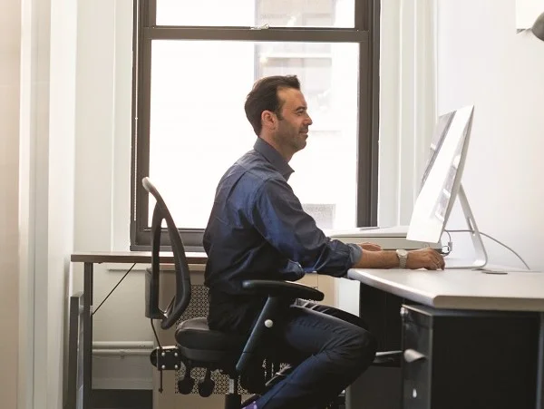 Office life. A man in casual clothing seated at a desk looking a