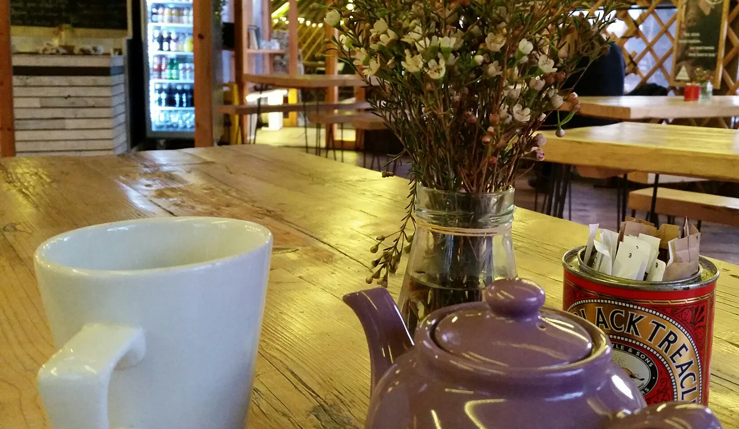 Teapot, cup and flowers on a cafe table.