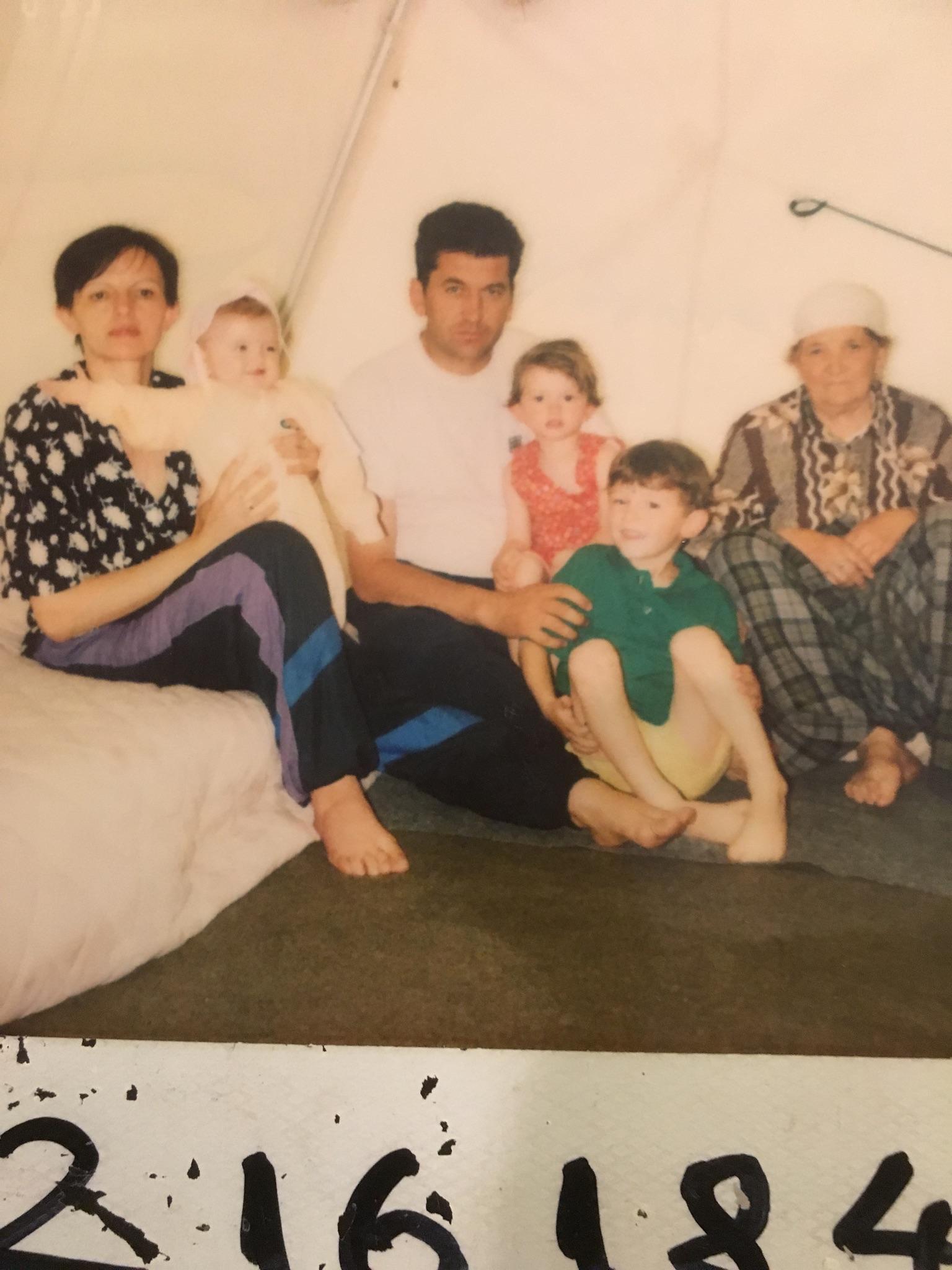 Petrit (center, in green shirt) in a refugee camp with his family. 