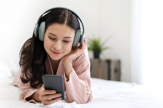 beautiful-young-woman-relaxing-listening-music-with-headphones-bed-home_38019-1427.jpeg