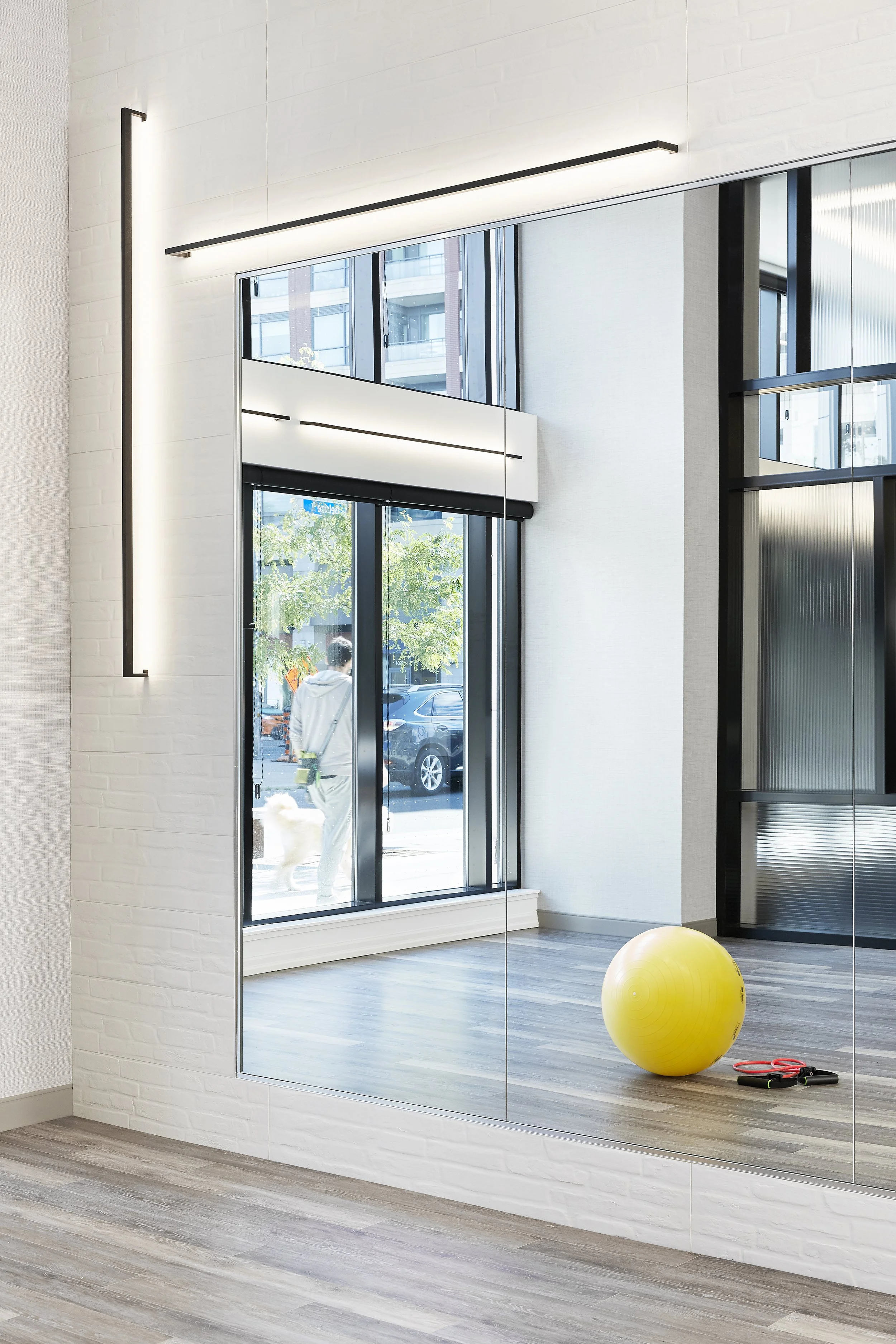 Yoga fitness studio at Mattamy Homes - J. Davis Condominium with large windows, yellow exercise ball, skipping rope, and mirrors on the wall.