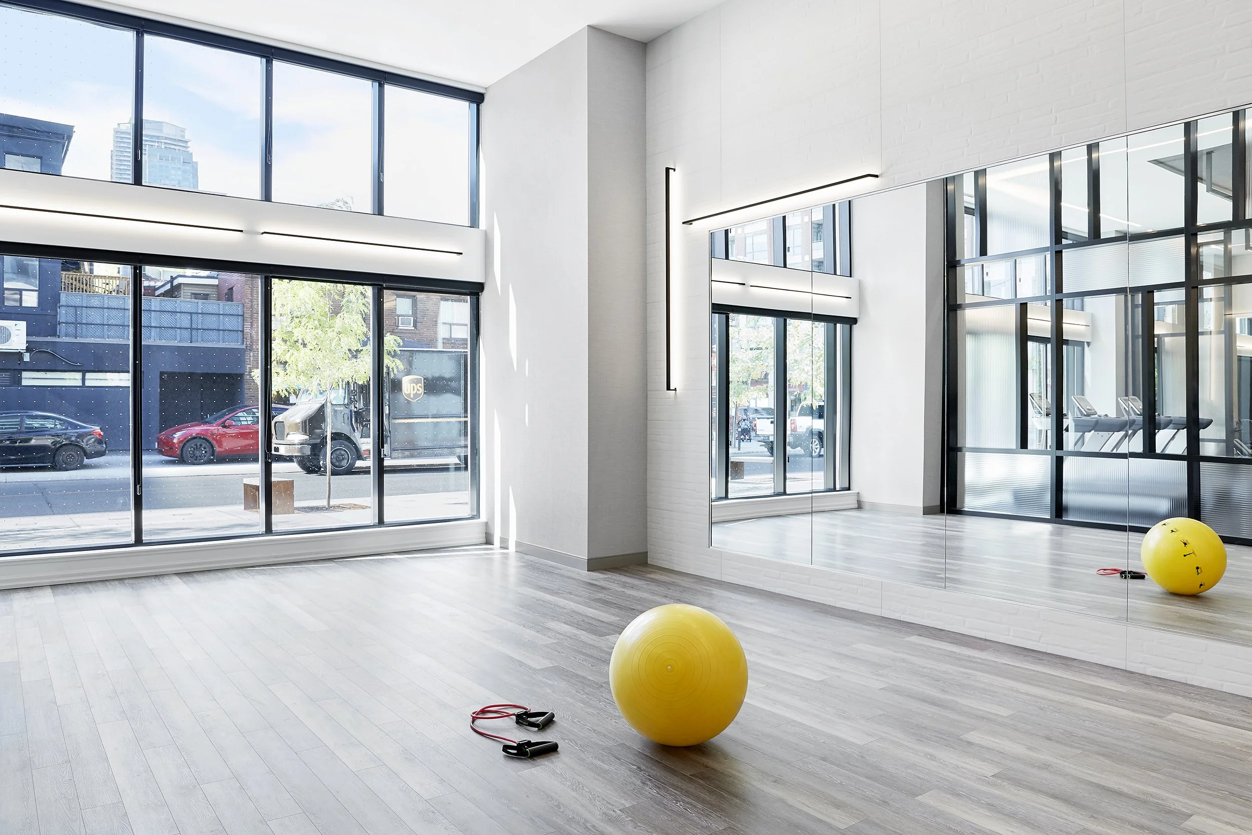 Yoga fitness studio at Mattamy Homes - J. Davis Condominium with large windows, yellow exercise ball, skipping rope, and mirrors on the wall.