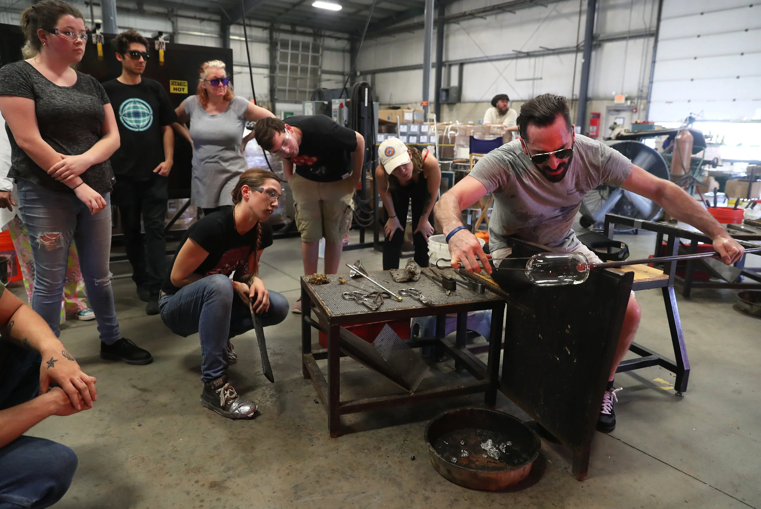 Instructor Alexander Rosenberg demonstrating how to create a glass cylinder in the hot shop.