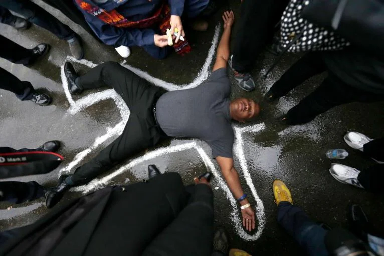 Ferguson, Missouri, activist/pastor Charles Burton lies on the ground to protest the death of Michael Brown. Photo courtesy of Charles Rex Arbogast/AP. 