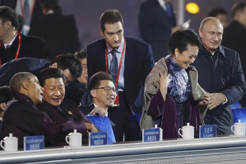 Vladmir Putin wraps shawl around Xi Jinping's wife Peng Liyuan as Xi chats with Obama at APEC summit, causing media frenzy. Source: AP.