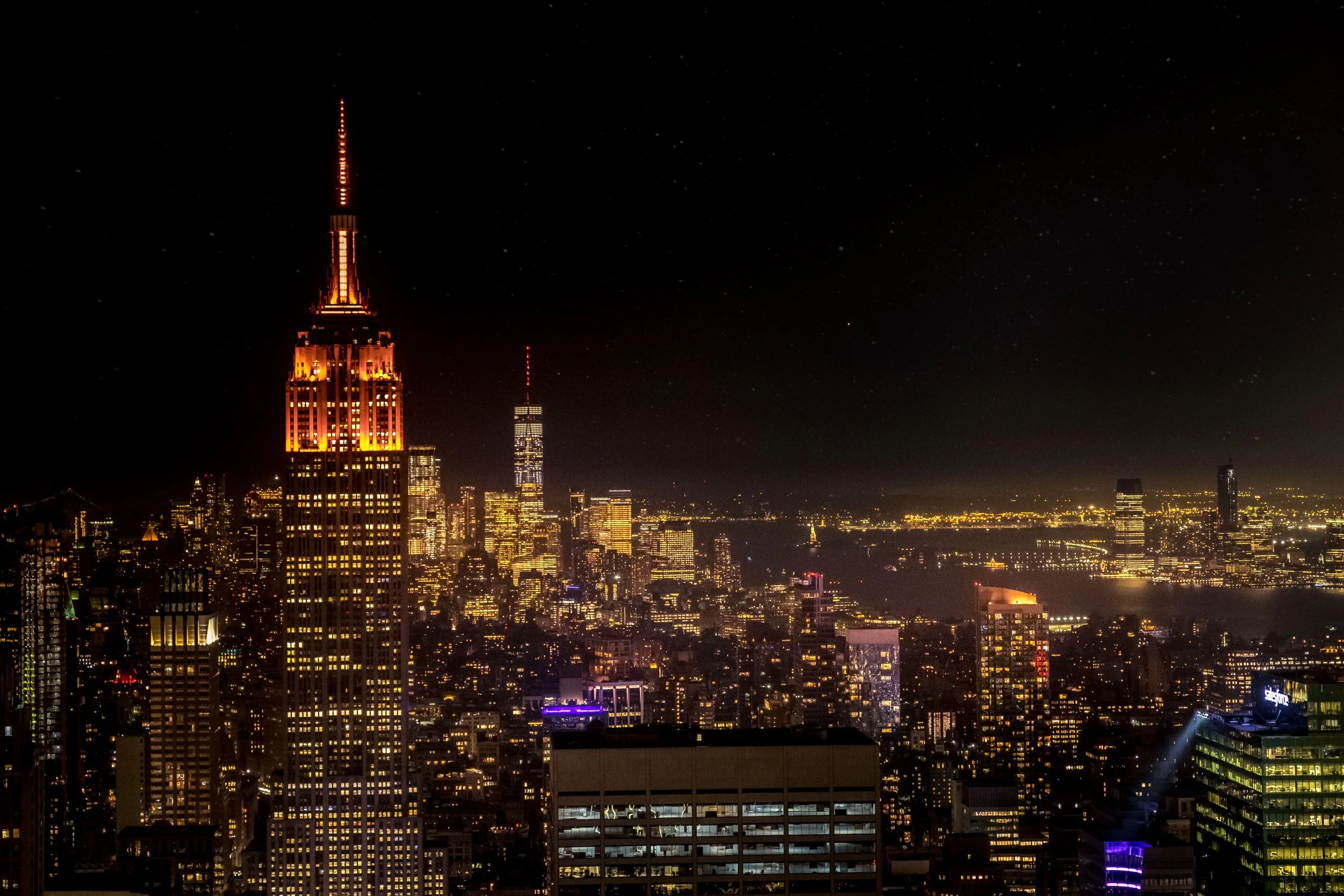 Manhattan skyline at night with the Empire State Building lit in orange