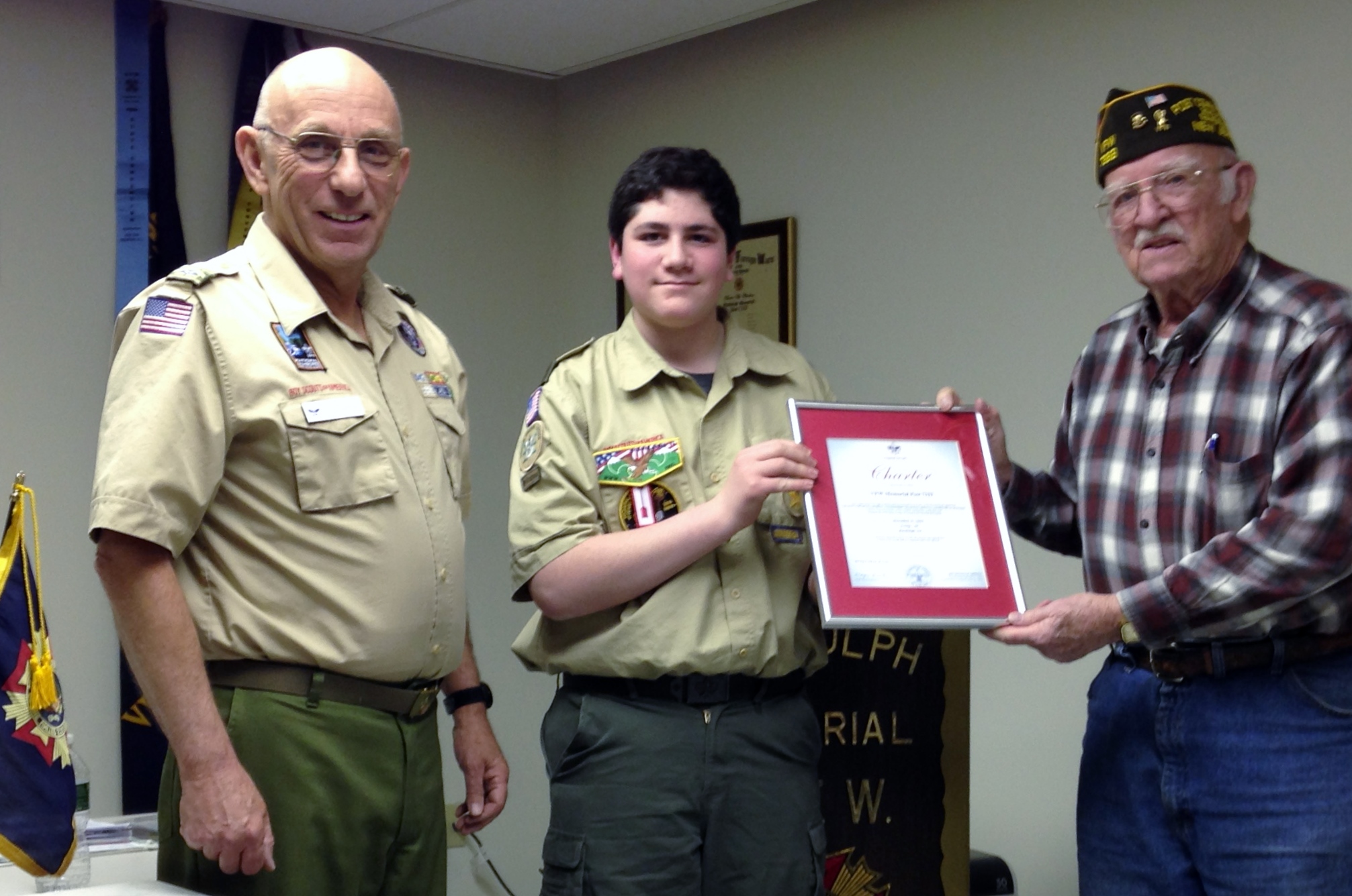Scout Master Ken and Troop 50 senior patrol leader Michael present the annual Boy Scout of America sponsor charter to past Post Commander Bob.