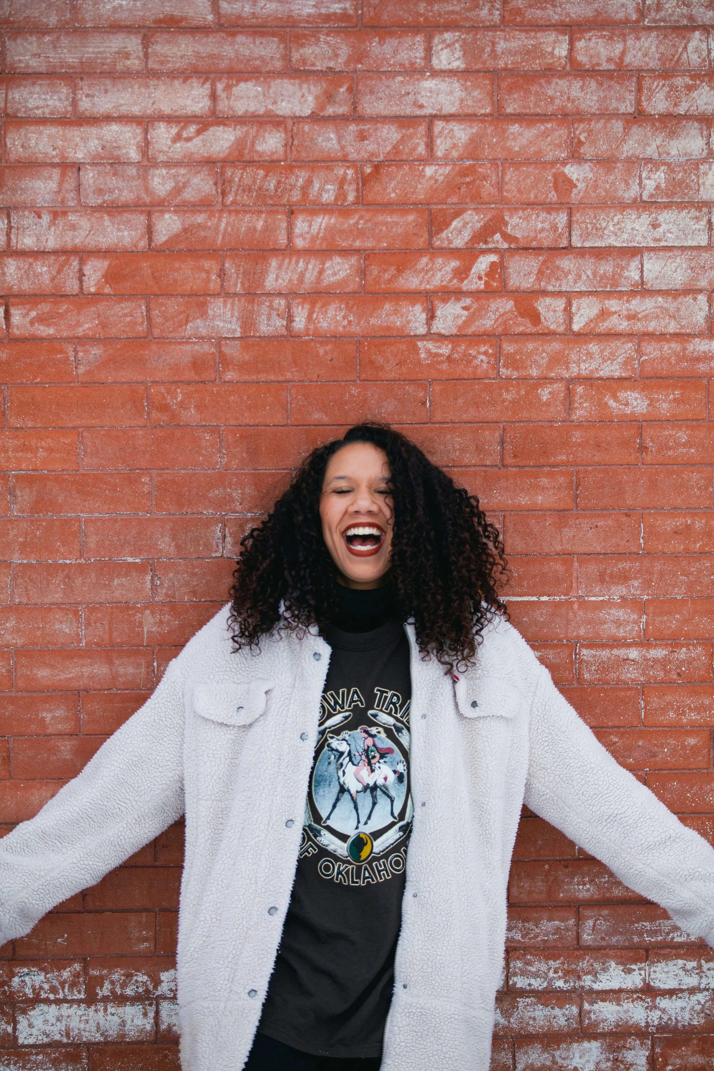  Joyful High-Quality Photo: Young Black Woman with Afro Laughing Against Brick Wall 