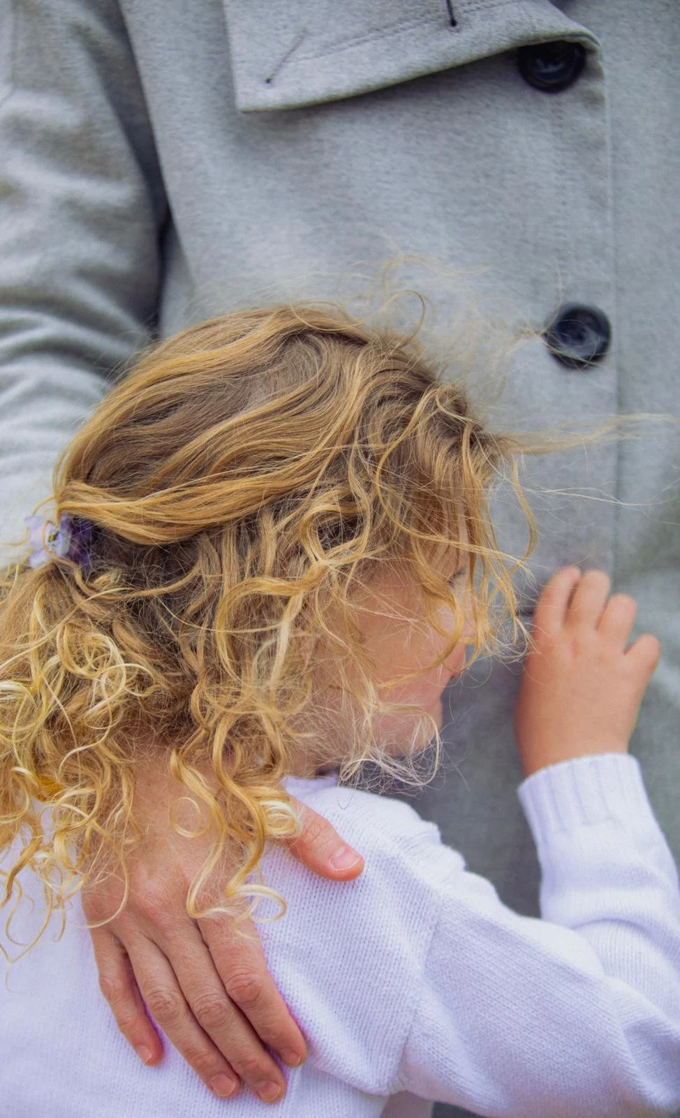  Delight in this high-quality portrait capturing a heartwarming moment as a young girl embraces her mother, both adorned in stylish peacoats. Experience the warmth and love emanating from this touching scene beautifully preserved in this expertly cra