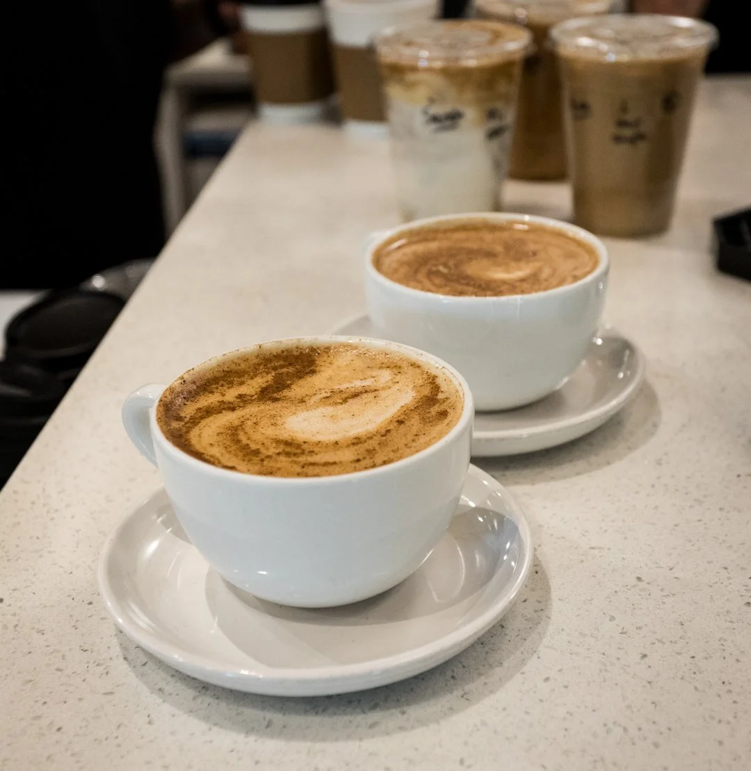 Two lattes and two to-go drinks ready at the counter.