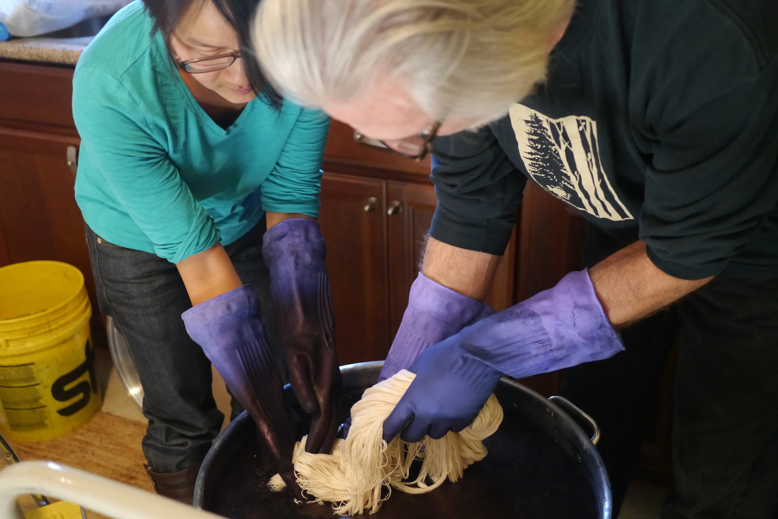 Slowly lowering the yarn into the fermented indigo vat, careful not to disturb the vat. K