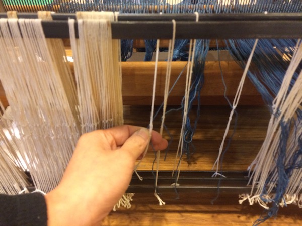  After we are finished threading the reed, we pull the indigo warp yarns through the homemade heddles.&nbsp; 