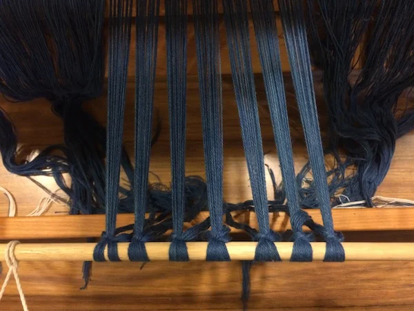 Tightening the warp yarns on the loom. 