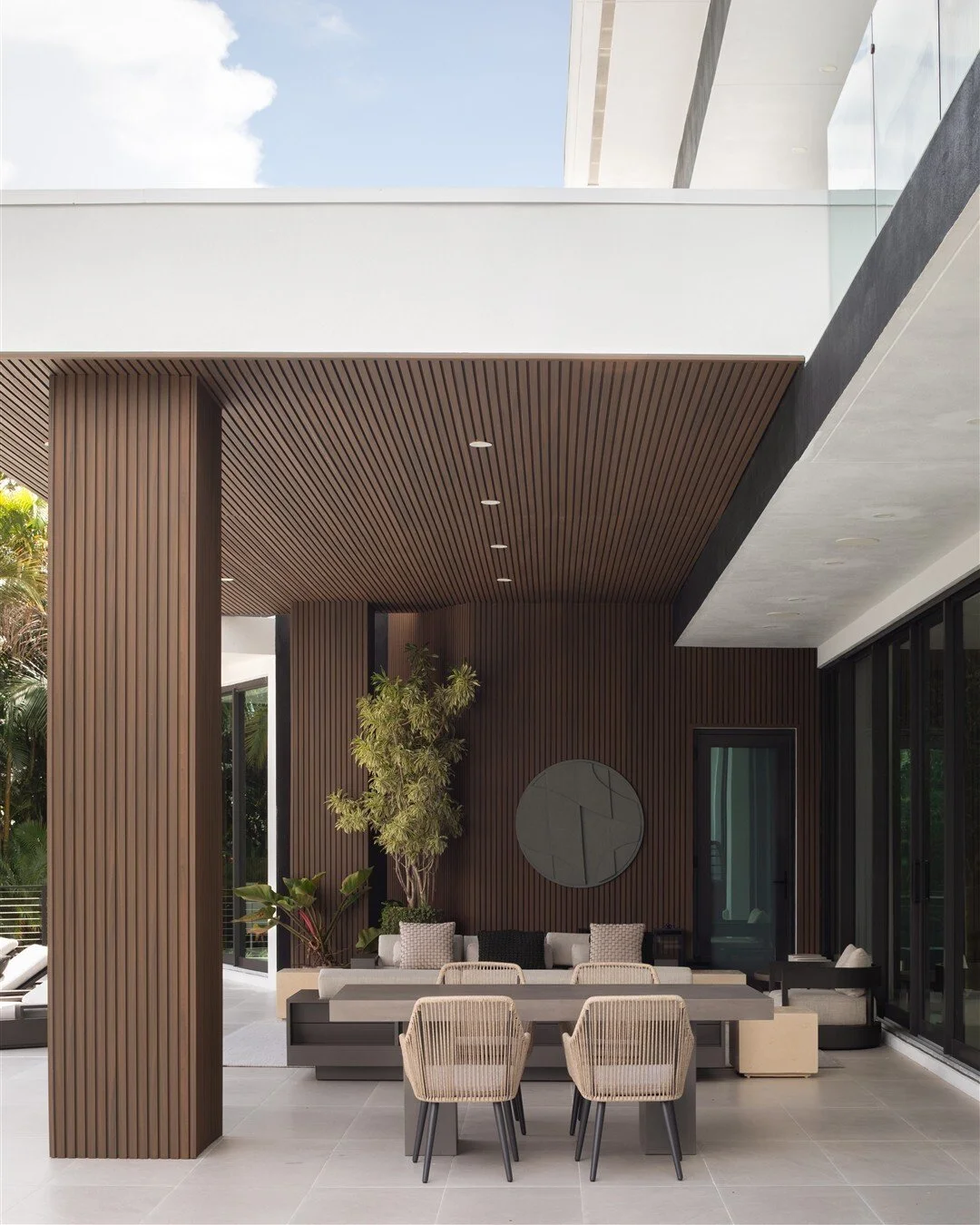 The patio feels like another room of the house, with the comfort of being indoors and a little more fresh air.

The wood ceiling helps define the seating and dining areas, while the open side keeps them connected to the pool. It&rsquo;s a balance tha