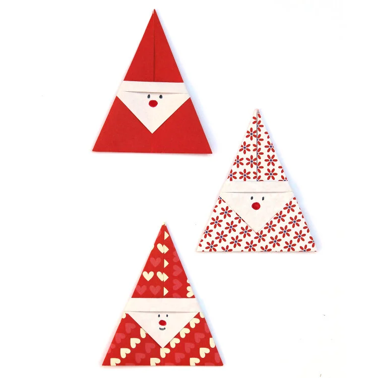 three red and white origami christmas santas on white background