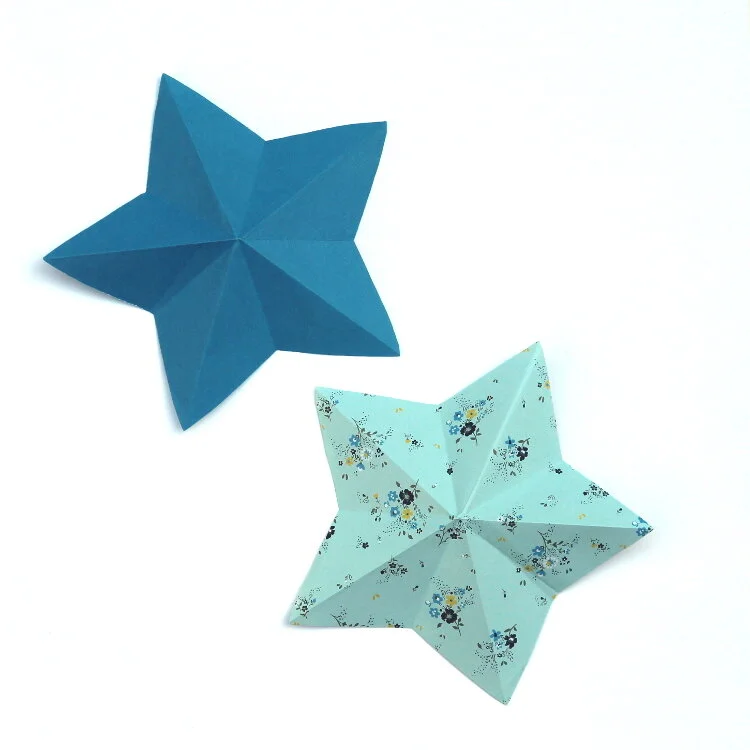 two blue origami stars on white background