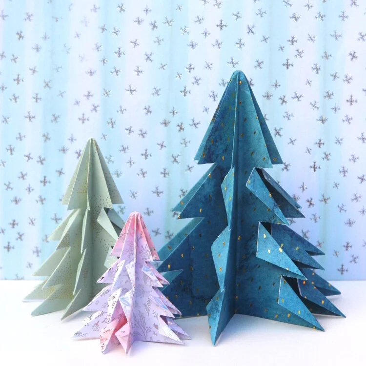 three origami christmas trees on blue and white background