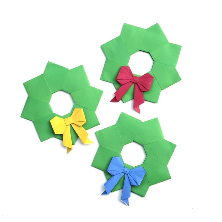 3 green origami wreaths with origami bows on them