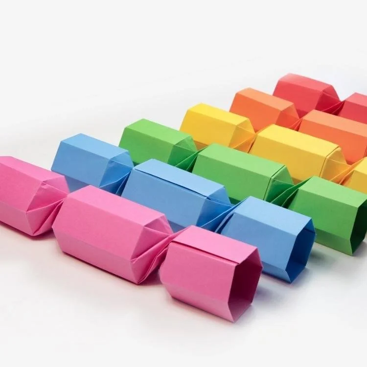 six rainbow coloured origami christmas crackers in a row