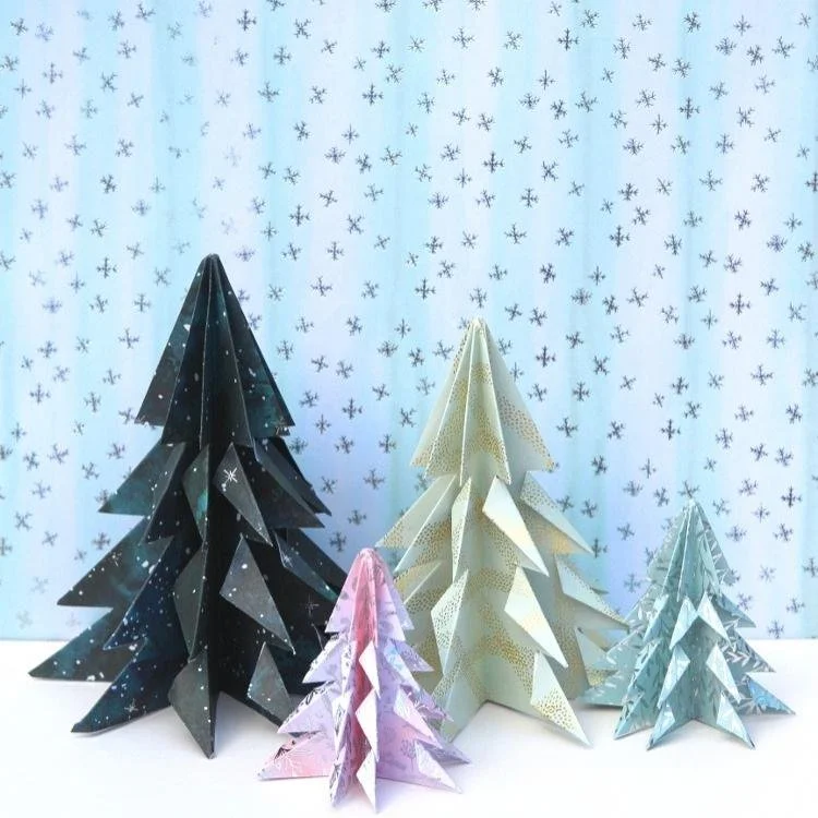 4 pastel coloured origami trees against a blue background