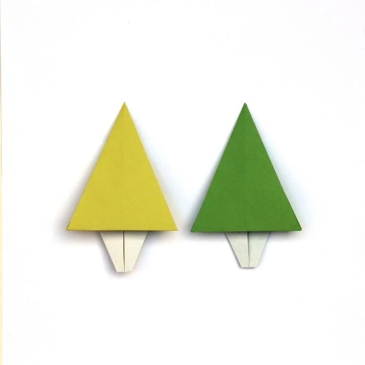 2 flat origami trees with green tops and white trunk