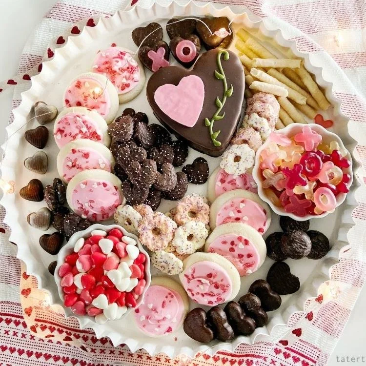 round plate filled with pink sprinkle cookies, chocolate hearts and pink valentines candy
