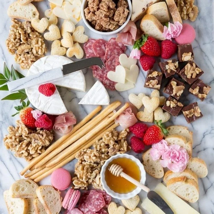 marble board covered with cheese, bread, nuts and honey