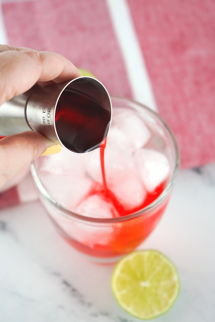 hand pouring grenadine over ice