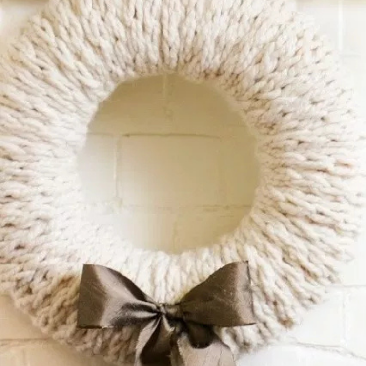 white wreath made from finger knitting with bow on