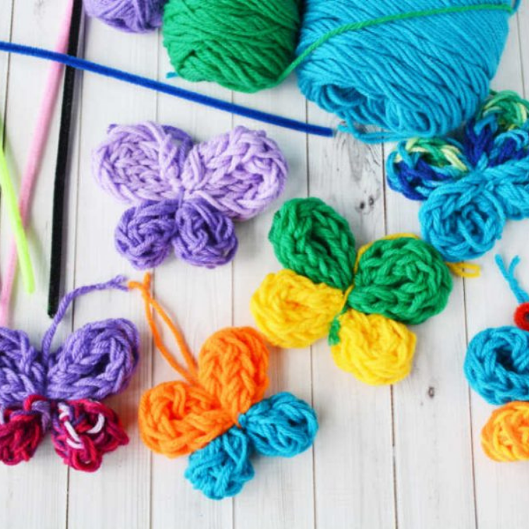 brightly coloured knitted butterflies on wooden background