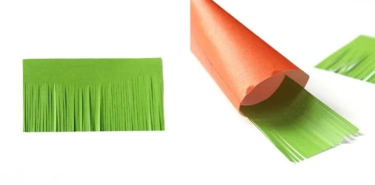 open orange paper tube with green fringe cut paper stuck inside