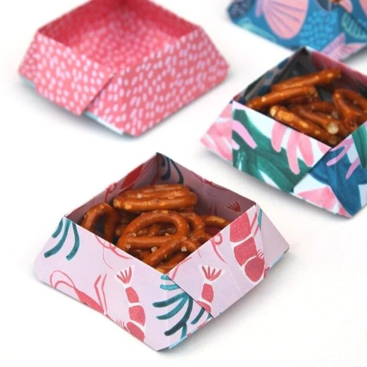 Origami square bowl filled with pretzels.
