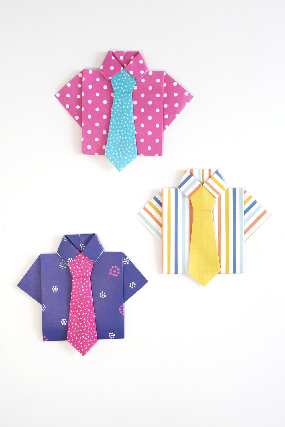 Three origami shirts and ties made out of brightly coloured patterned paper.