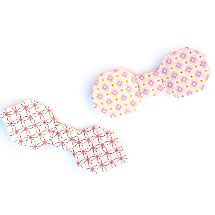 Origami bow ties made out of cream and pink patterned paper.