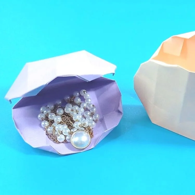Lilac origami oyster shell filled with pearls and jewelery.