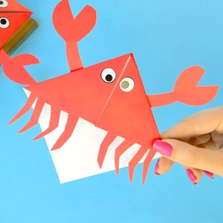 Origami corner bookmark decorated to look like a crab.